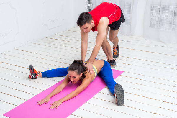 Coach helping the girl to stretch the waist Stock Photo