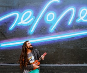Fashionable man playing guitar under neon lights Stock Photo