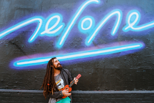 Fashionable man playing guitar under neon lights Stock Photo