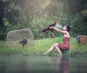 Girl holding a rooster in the river Stock Photo