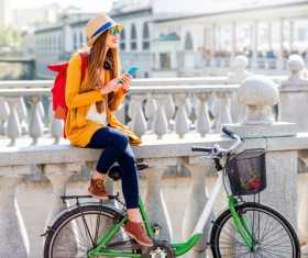 Girl sitting on bridge bar using smartphone to listen music Stock Photo
