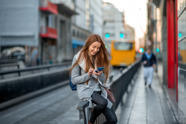 Girl sitting on the parapet playing phone Stock Photo