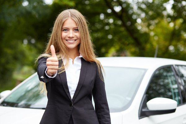 Girl with thumbs up in front of the car Stock Photo