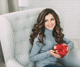 Happy girl sitting on the couch holding Christmas gift Stock Photo 01
