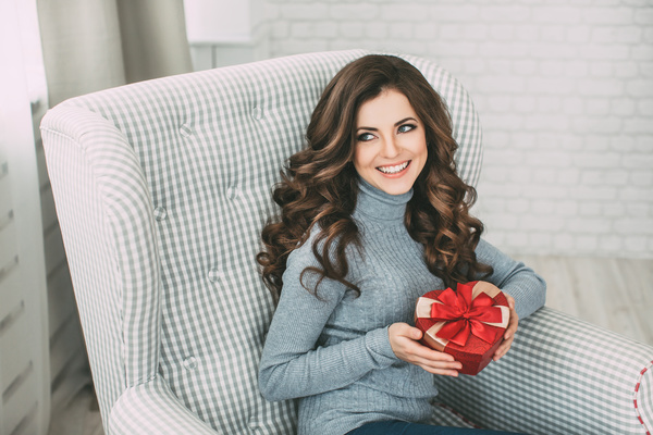 Happy girl sitting on the couch holding Christmas gift Stock Photo 01