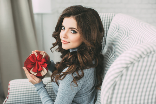 Happy girl sitting on the couch holding Christmas gift Stock Photo 02
