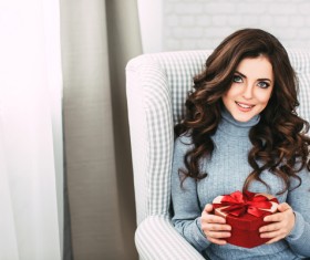 Happy girl sitting on the couch holding Christmas gift Stock Photo 03