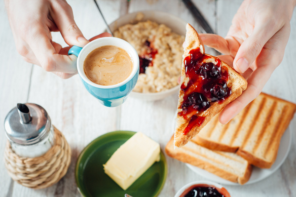 Holding coffee and a slice of bread with jam Stock Photo