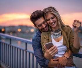 Hugging couple looking at cellphone Stock Photo