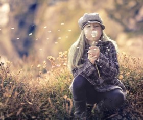 Little girl blowing dandelion flowers Stock Photo