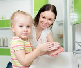 Little girl washing hands with mother Stock Photo