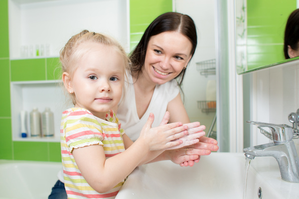Little girl washing hands with mother Stock Photo
