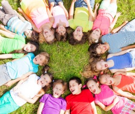 Lying in the grass in a circle of children Stock Photo