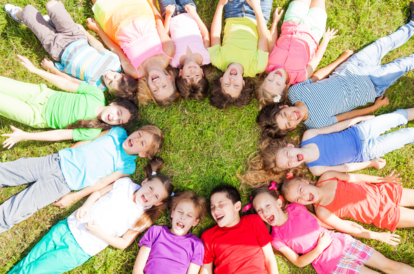 Lying in the grass in a circle of children Stock Photo