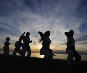 Men and women practicing martial arts in the early morning on the beach Stock Photo
