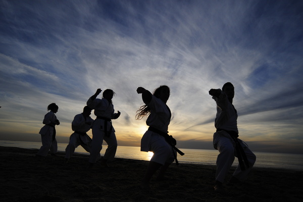Men and women practicing martial arts in the early morning on the beach Stock Photo