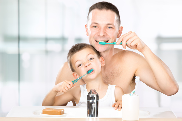 Smiling child brushes his teeth with dad Stock Photo 02