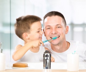 Smiling children help daddy brush his teeth Stock Photo