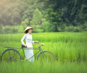 Vietnamese girl pushing bicycle standing in farmland Stock Photo