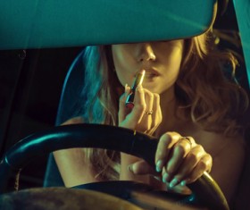 Woman sitting in limousine applying lipstick Stock Photo