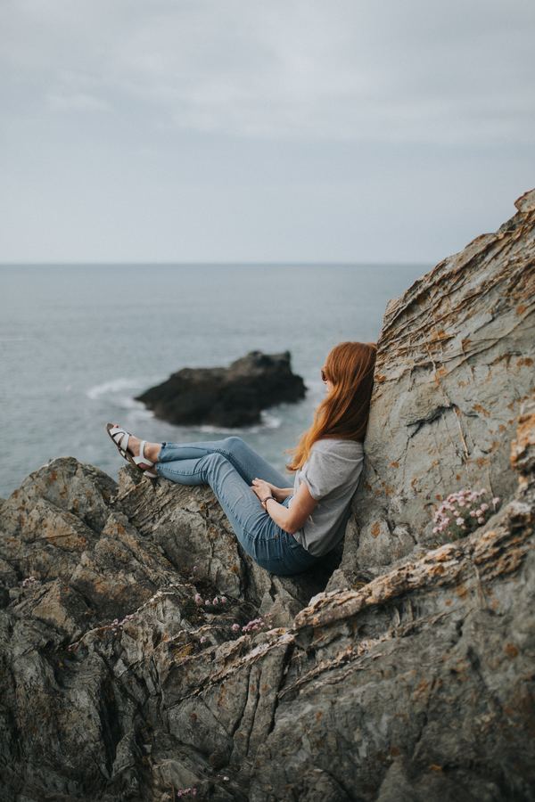Woman sitting on the beach rocks Stock Photo