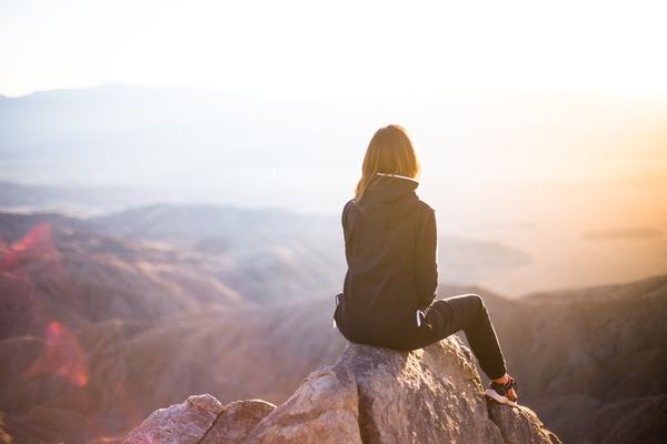 Woman sitting on the peak watching the sunrise Stock Photo