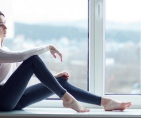 Beautiful charming woman sitting on windowsill Stock Photo
