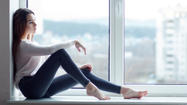 Beautiful charming woman sitting on windowsill Stock Photo