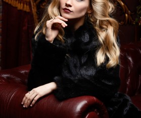 Blonde girl in black mink coat sitting on the couch Stock Photo 02