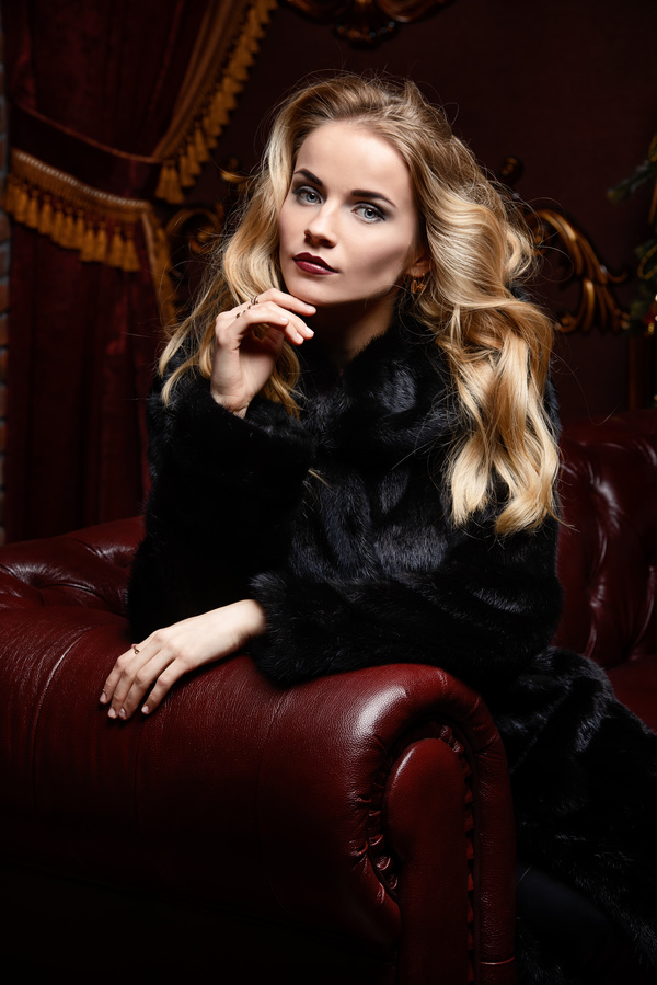 Blonde girl in black mink coat sitting on the couch Stock Photo 02