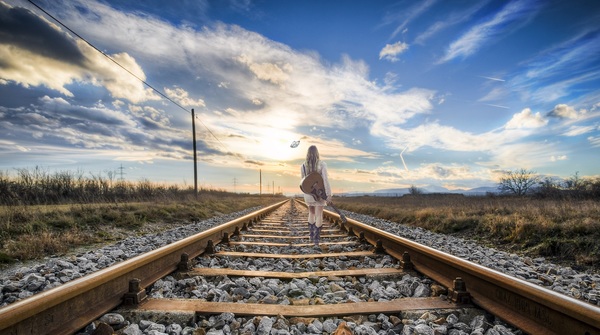 Carrying musical instrument girl walking on the tracks Stock Photo