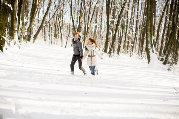 Couple running in winter snow outdoors Stock Photo