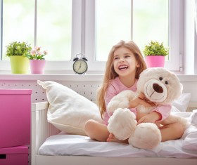 Little girl sitting in bed hugging teddy bear Stock Photo