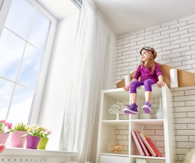 Little girl sitting on the wall cabinet Stock Photo