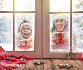 Mother and daughter holding Christmas gift outside the window Stock Photo