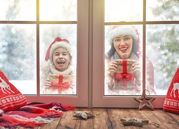 Mother and daughter holding Christmas gift outside the window Stock Photo