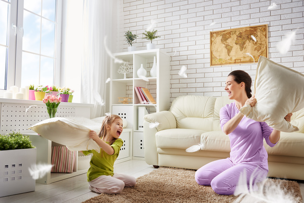Mother and daughter holding pillows in the living room Stock Photo