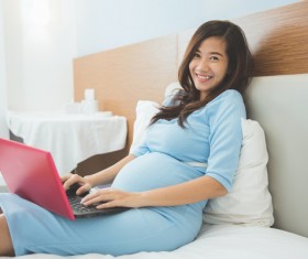 Pregnant woman in bed using laptop Stock Photo