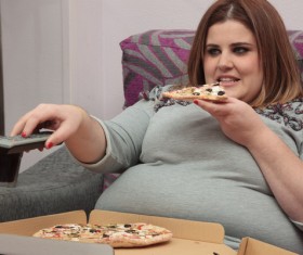 Woman eating pizza watching TV Stock Photo