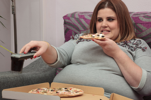 Woman eating pizza watching TV Stock Photo