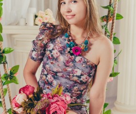 Woman sitting on swing holding flowers Stock Photo