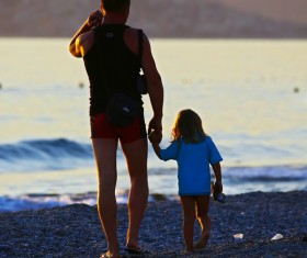 Father and daughter walking on the beach Stock Photo