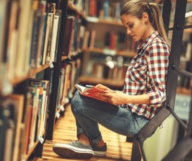 Female student reading book in the library Stock Photo