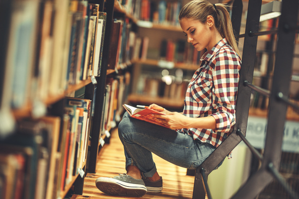 Female student reading book in the library Stock Photo
