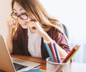 Girl biting pencil working in front of laptop Stock Photo
