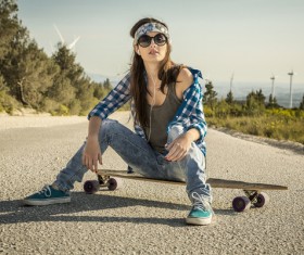 Girl sitting on skateboard listening to music Stock Photo