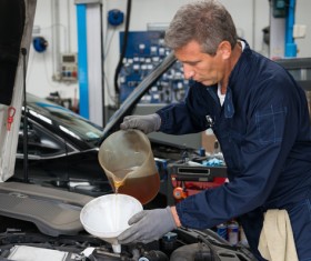 Maintenance workers to the car plus oil Stock Photo