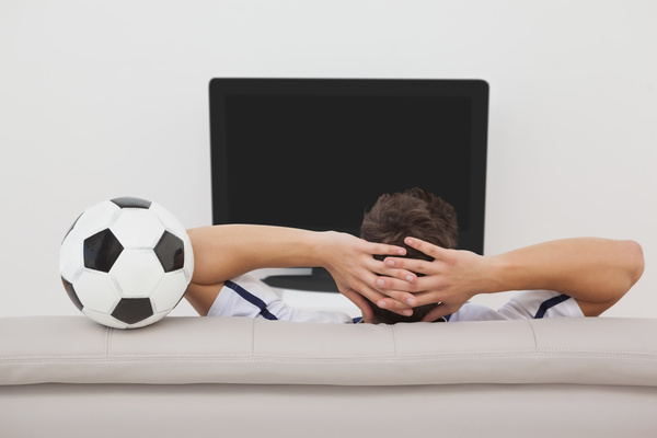 Man sitting on sofa watching game Stock Photo
