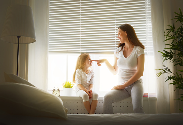 Mother and daughter sitting on the windowsill happy Stock Photo