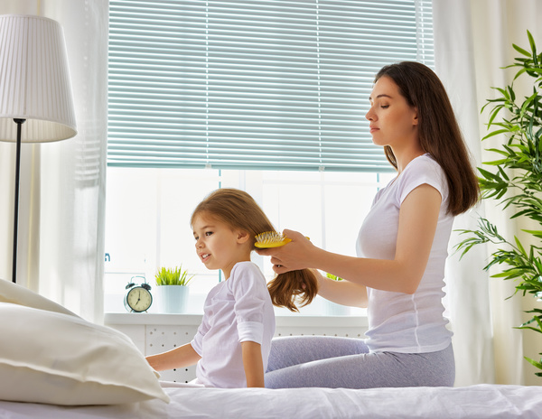 Mother combs hair for daughter Stock Photo